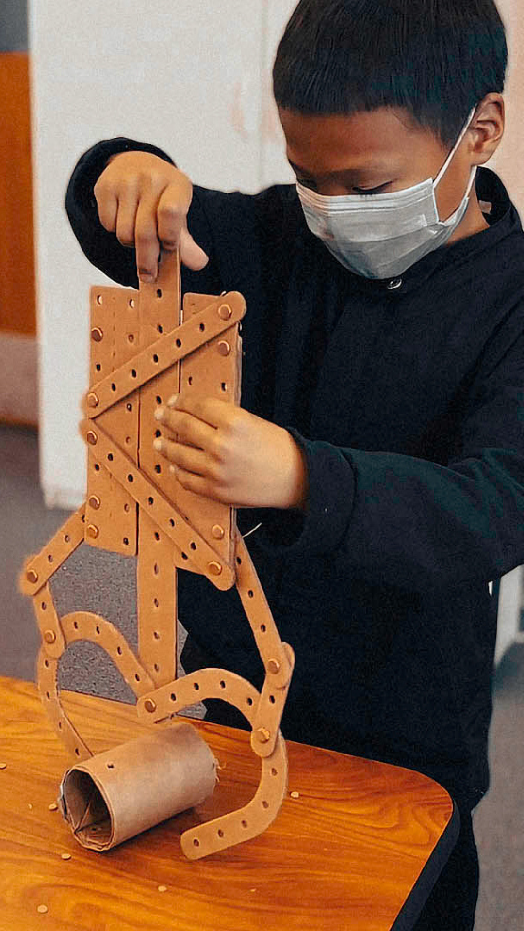 A kid using a Robotic Arm he made, to pull up a carboard roll